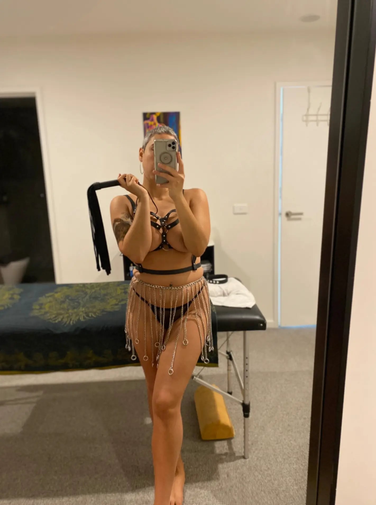 Erotic massage Melbourne, masseuse in a leather harness and chain skirt holding a flogger Erotic massage Melbourne, masseuse in a leather harness and chain skirt holding a flogger